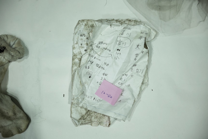 A sheet with basic Korean language notes is displayed among the other belongings.