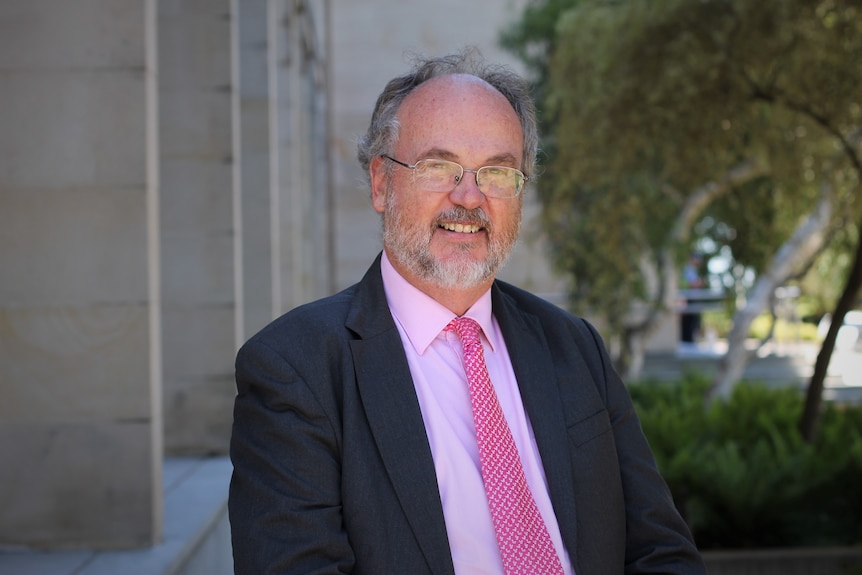 A portrait shot of Bill Johnston with state parliament building in background