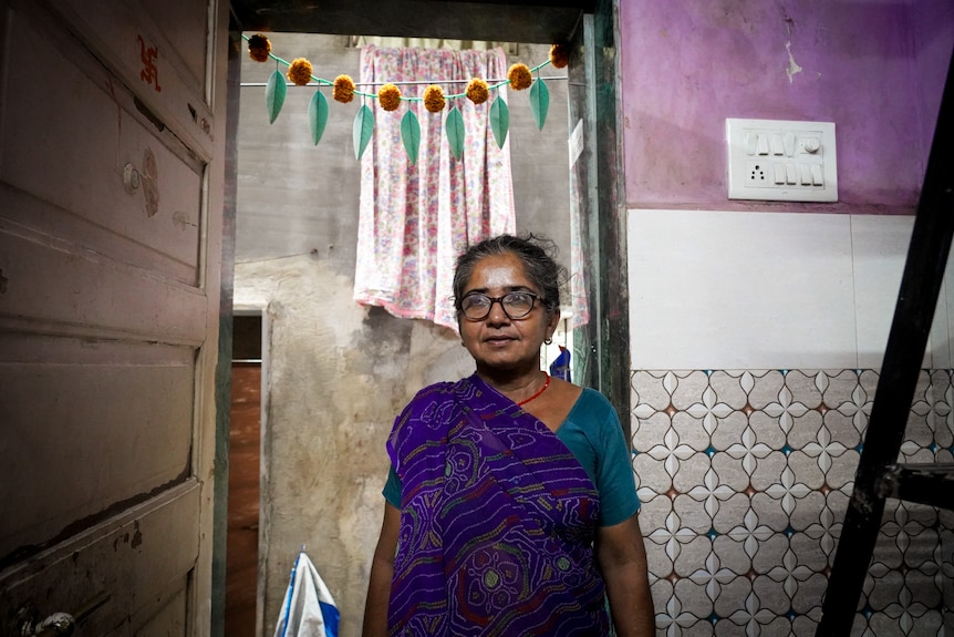 A woman in a purple sari standing in a doorway 