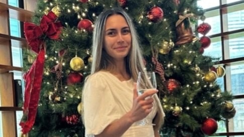 a woman standing in front of a christmas tree in a white dress