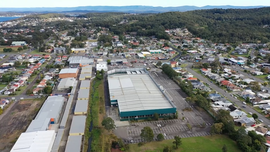 A large empty green warehouse in a busy suburb.