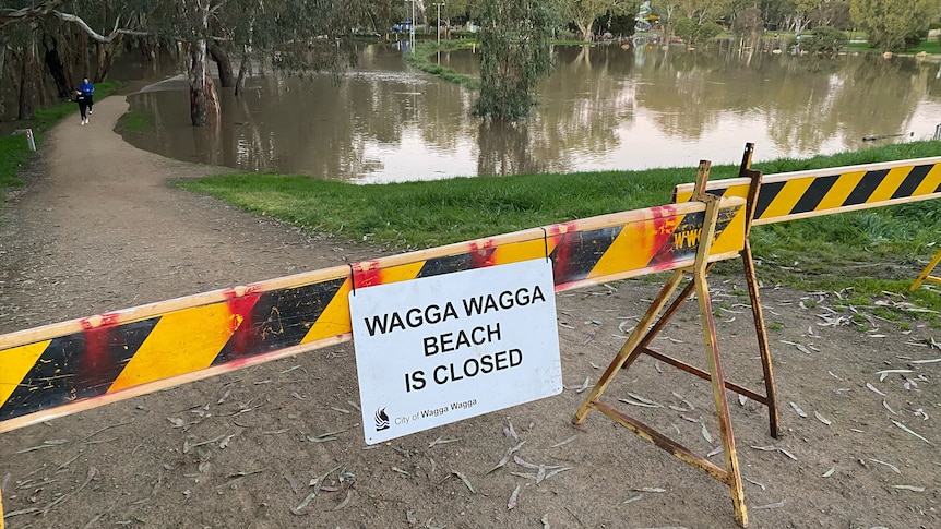 A sign saying Wagga Beach is closed near a large body of water