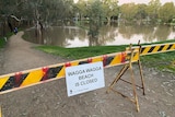 A sign saying Wagga Beach is closed near a large body of water