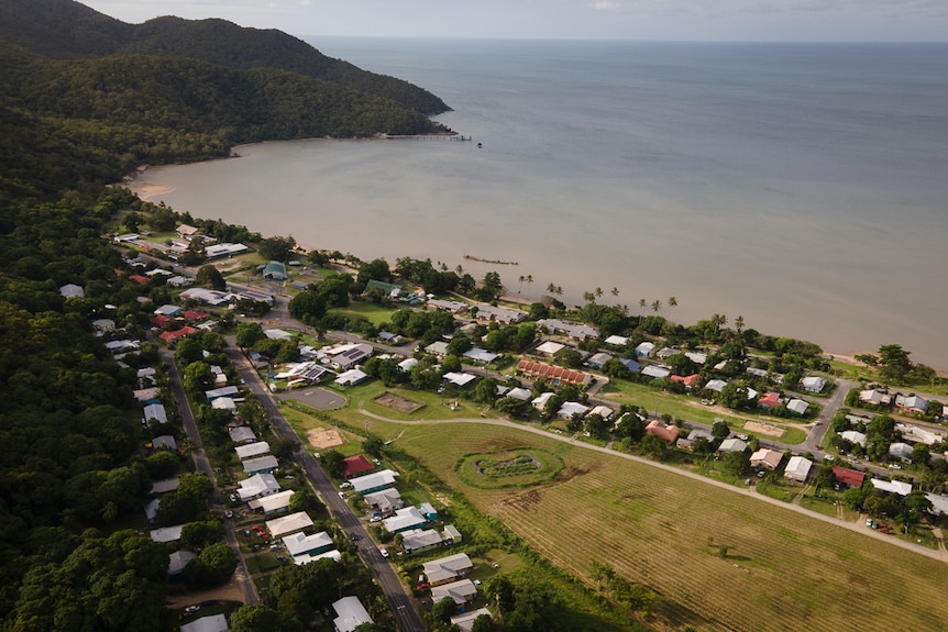 aerial of indigenous community near ocean with mountain range in background