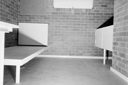 A black and white photo of a bed in a brick cell at Canberra's Quamby Remand Centre.