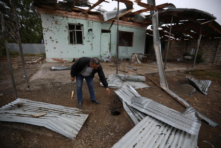 A man points on a hole from ammunition near a house that was allegedly damaged by recent shelling.
