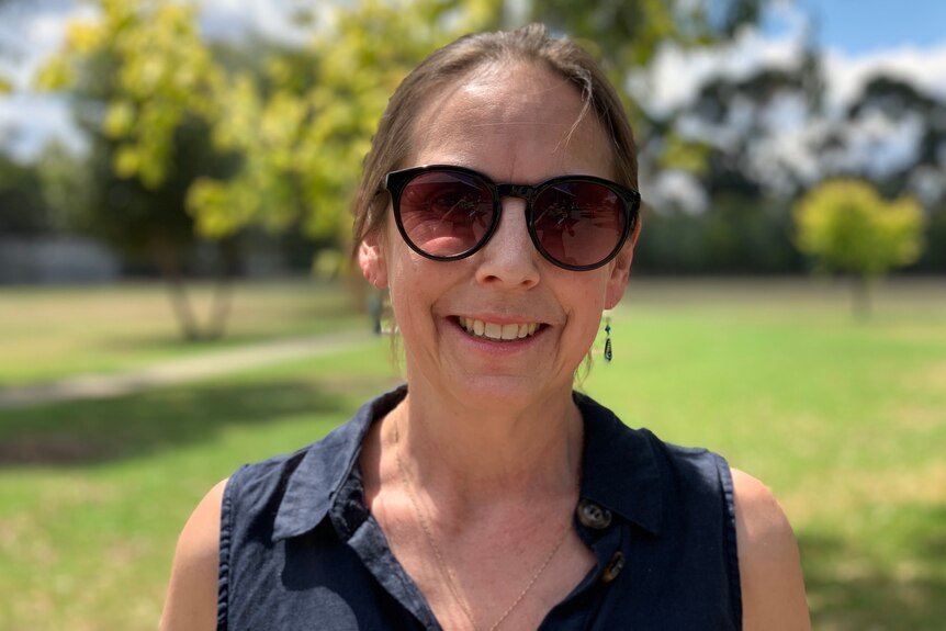 Hannah Robertson is wearing large sunglasses and smiling at the camera.