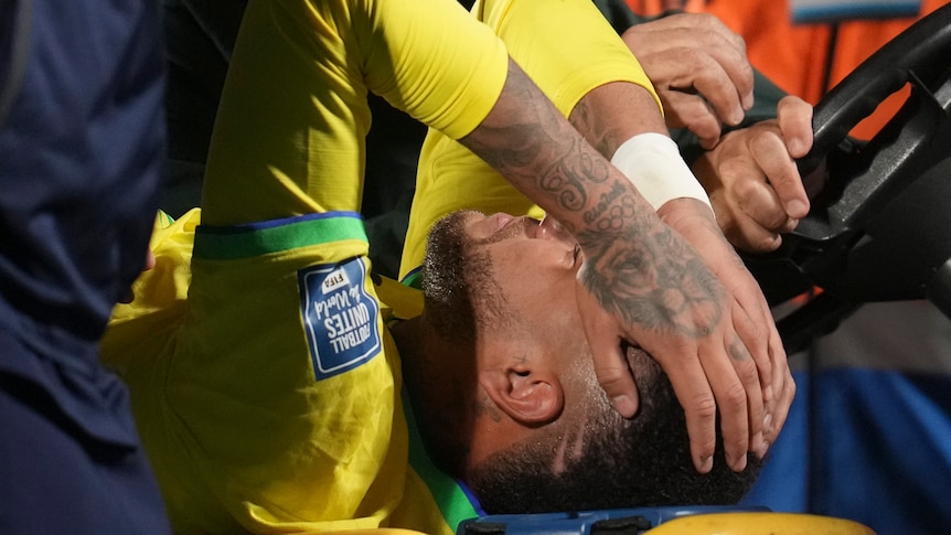 Neymar holds his head, lying on a stretcher