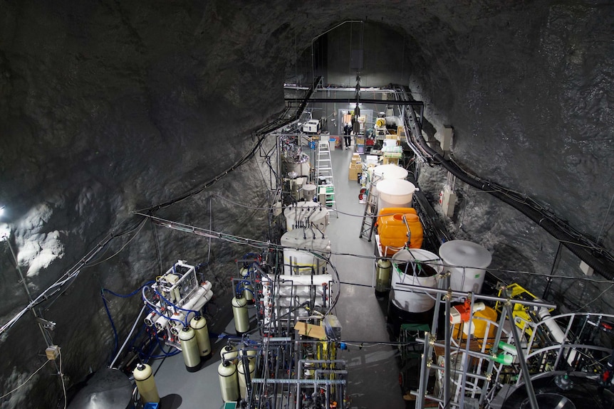 Vats, pipes and other scientific equipment are seen from above at an underground laboratory.