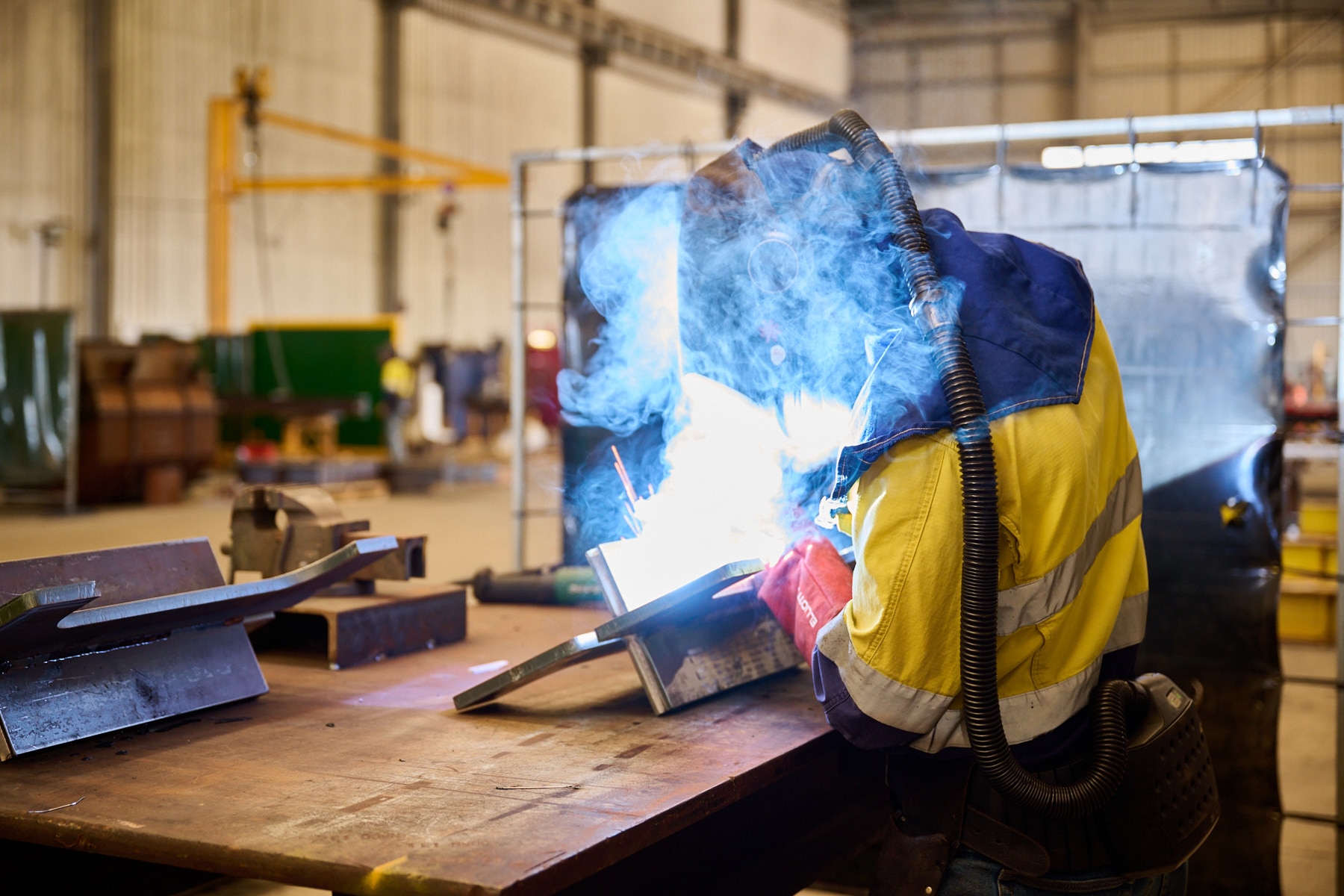 A person wears a face mask, helmut, and ventilation equipment while welding