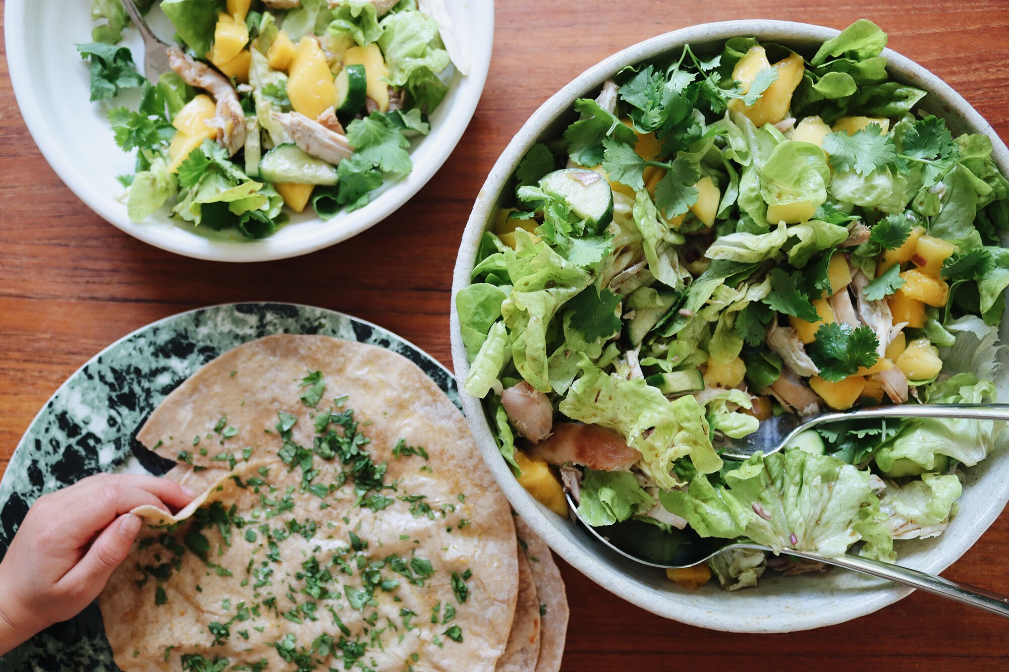 Chicken and mango salad served in a big bowl alongside wraps brushed in garlic butter, a light and fresh salad dinner.