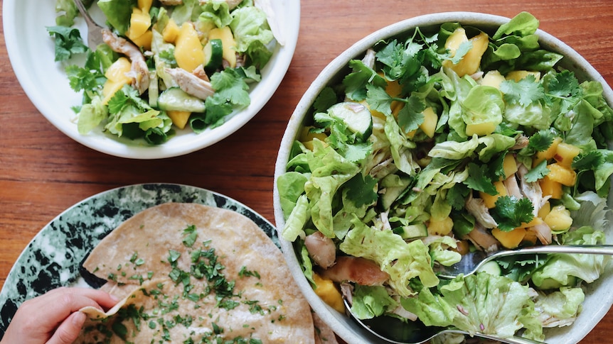 Chicken and mango salad served in a big bowl alongside wraps brushed in garlic butter, a light and fresh salad dinner.