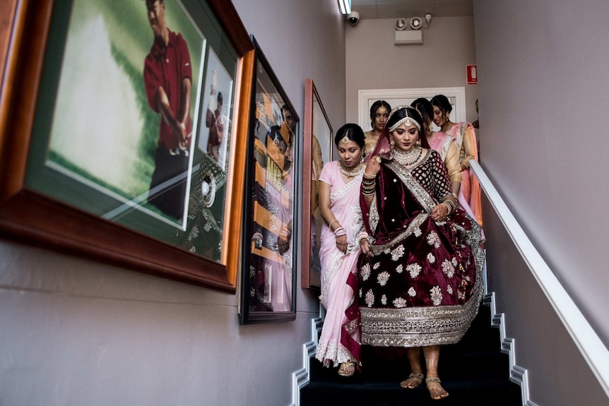 The bridal party heads downstairs past a photo of Tiger Woods.