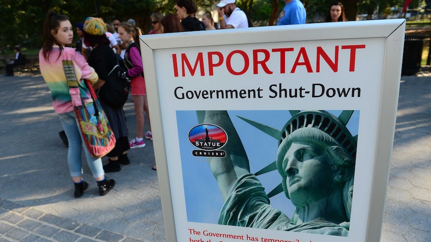 Tourists near a sign saying the Statue of Liberty is closed