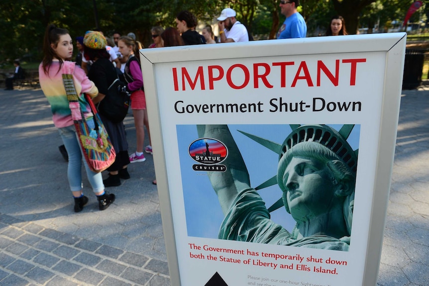 Tourists near a sign saying the Statue of Liberty is closed