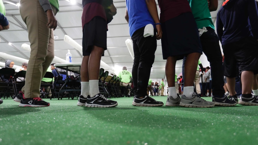 Young boys lined up inside a large cafeteria