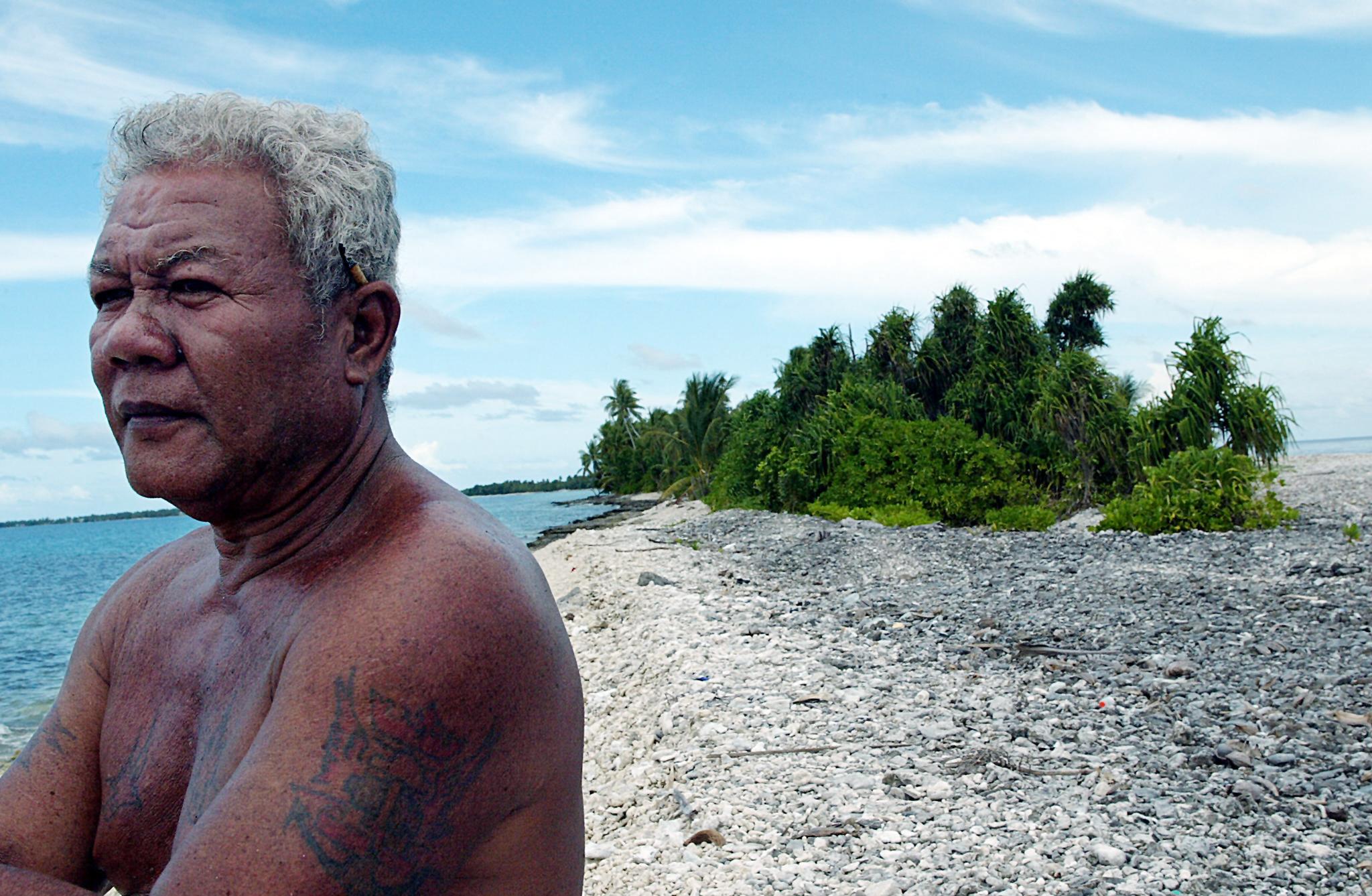 A fisherman looks out to sea at high tide from the shores of Funafuti Atoll.