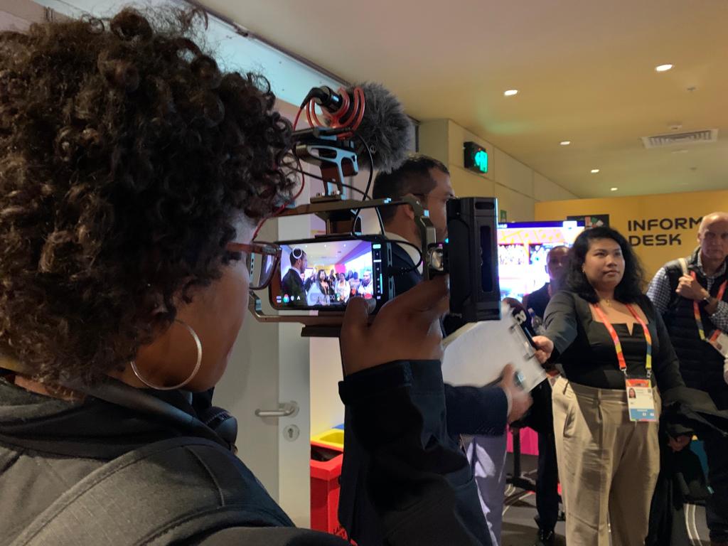 Woman operating a mobile phone camera kit, filming a woman doing an interview.