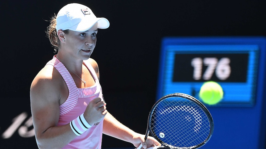 A female tennis player clenches her fist and smiles