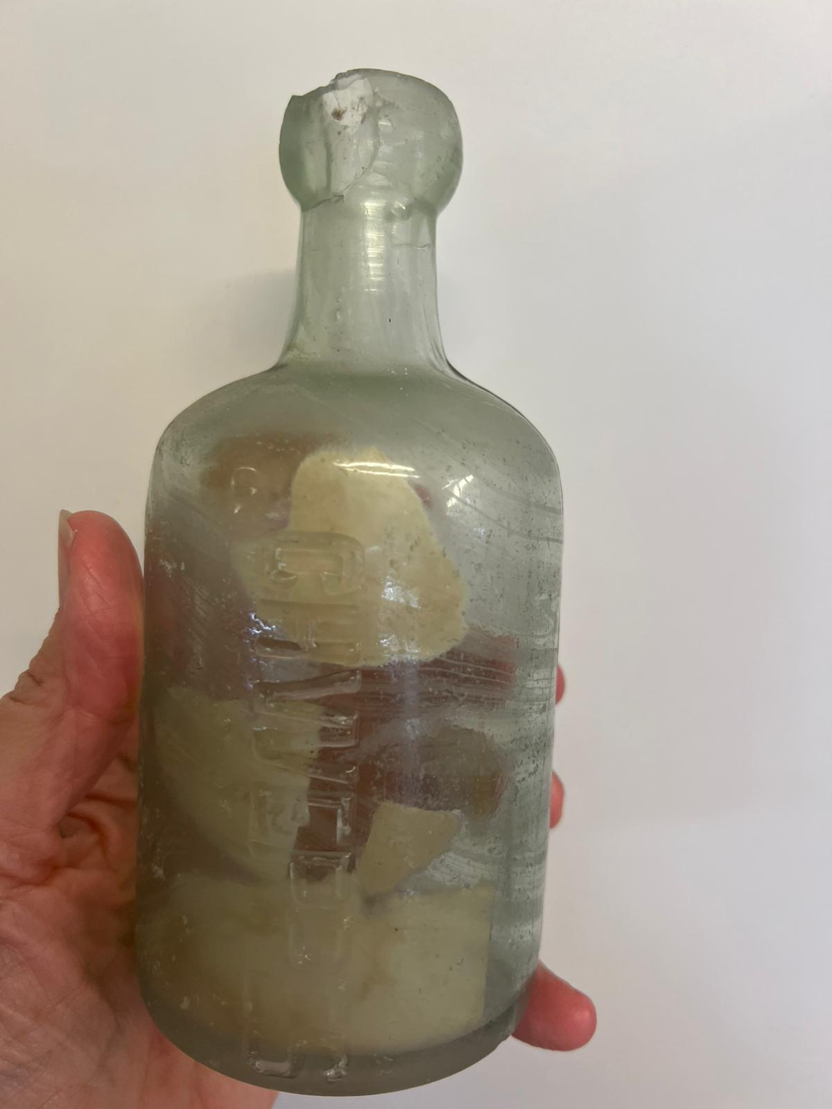 a hand holding an old bottle