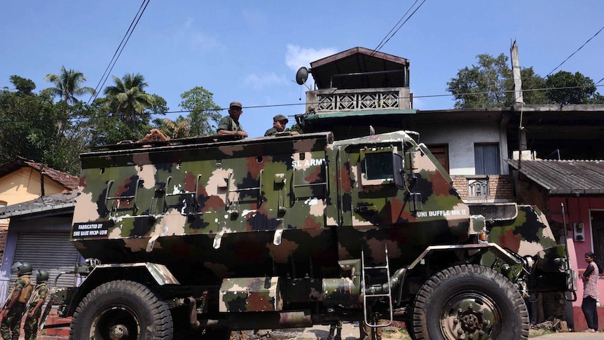 Sri Lankan army soldiers look on from an armed personnel carrier