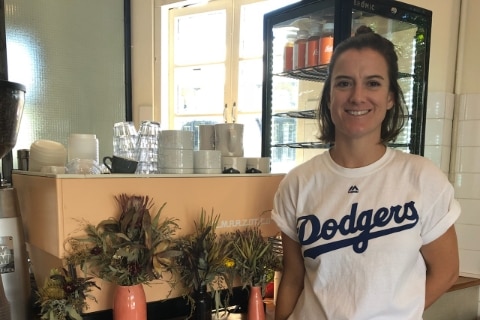 Woman standing in front of a coffee machine in a cafe, smiling