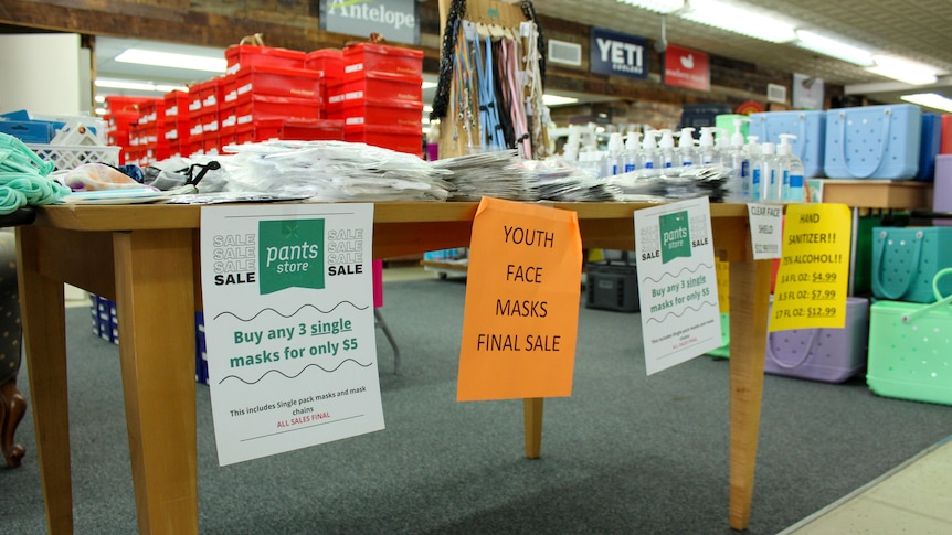 A table full of face masks and hand santiser bears "half-off" signs 