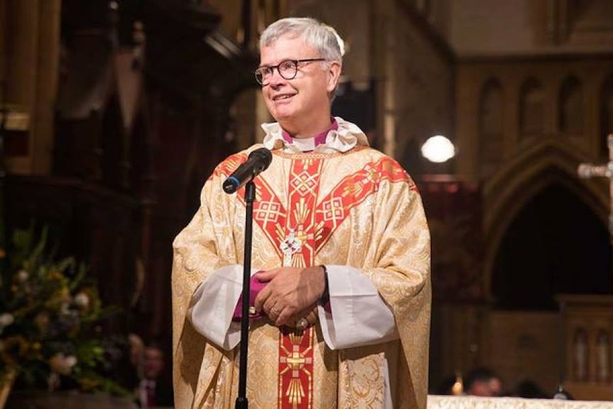 Bishop Peter Stuart stands at a microphone in church.