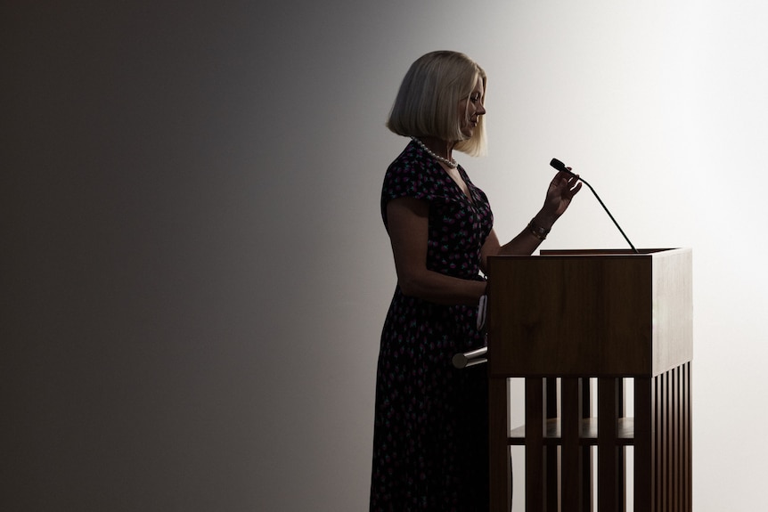 A woman stands at a podium