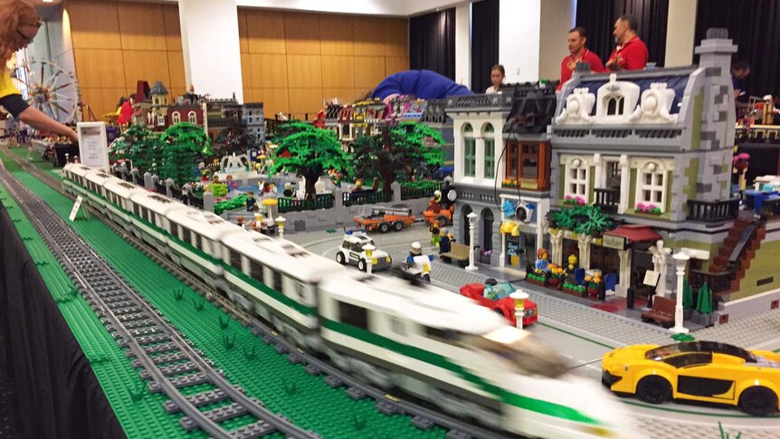 A Lego train turns a corner on a Lego track.
