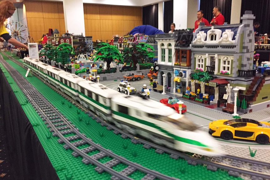A Lego train turns a corner on a Lego track.