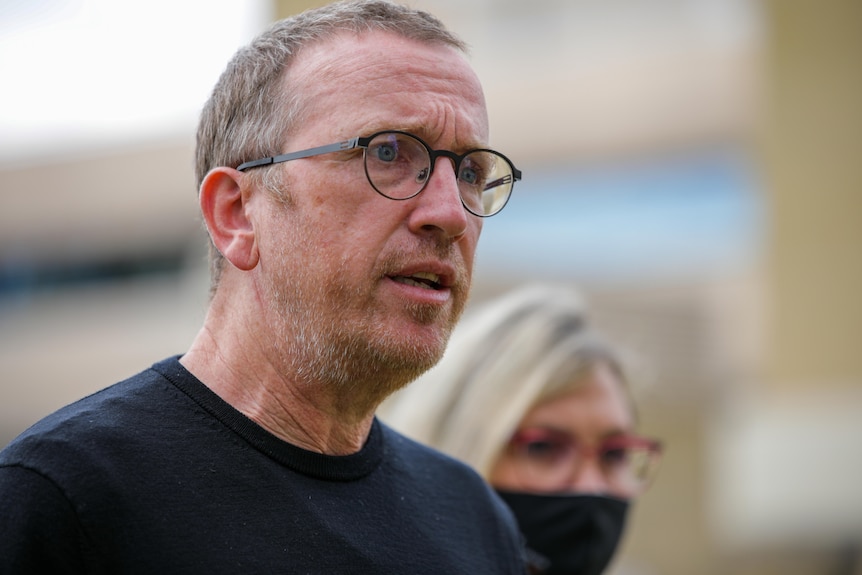 A man with glasses looks distressed while talking.