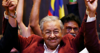 Mahathir Mohamad raises his arms at a press conference