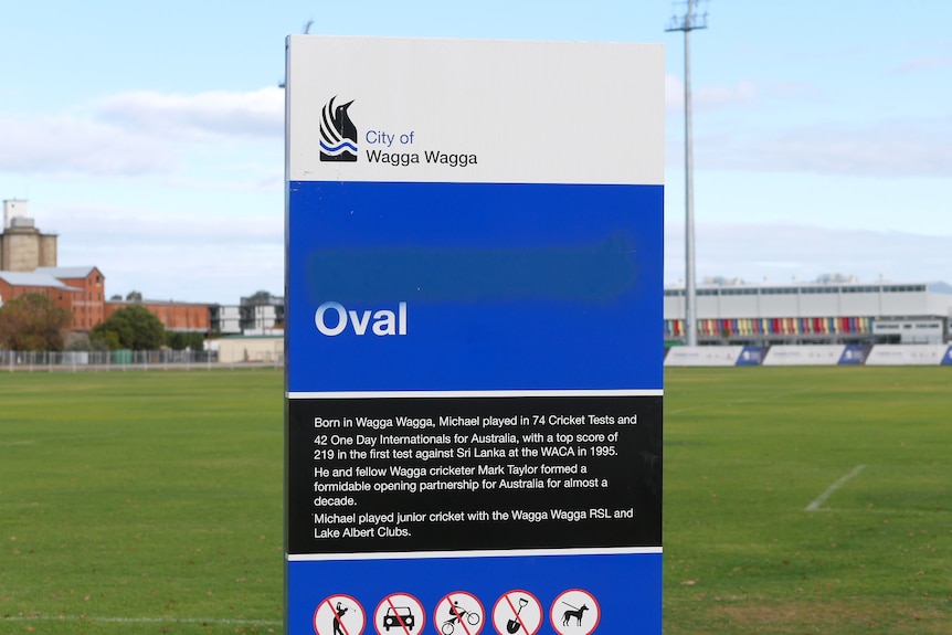 a blue, black and white sign in the middle of a sporting field.