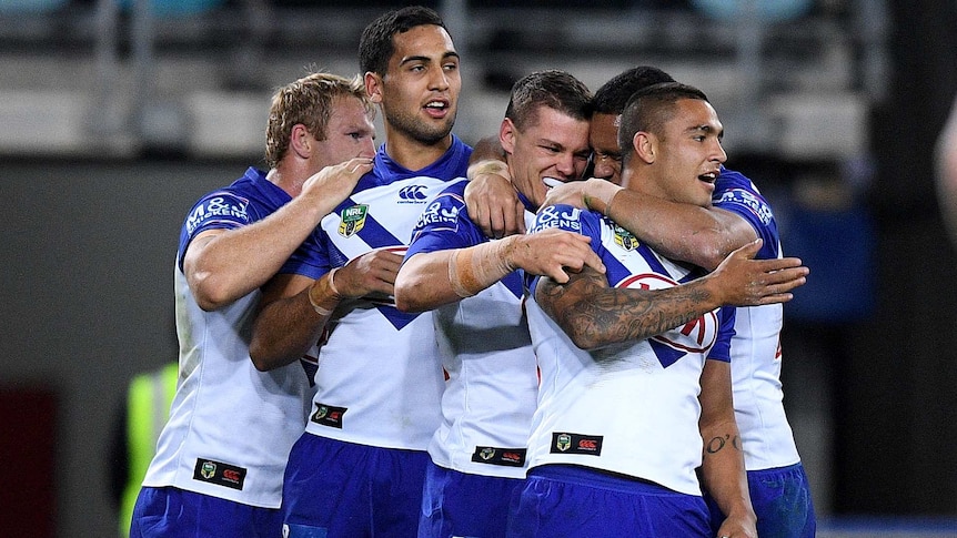 Kerrod Holland of the Bulldogs (C) celebrates with teammates after his try against Wests Tigers.