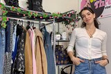 Esta Musumeci standing in front of a rack of clothing, in a story about turning side projects into paid work.