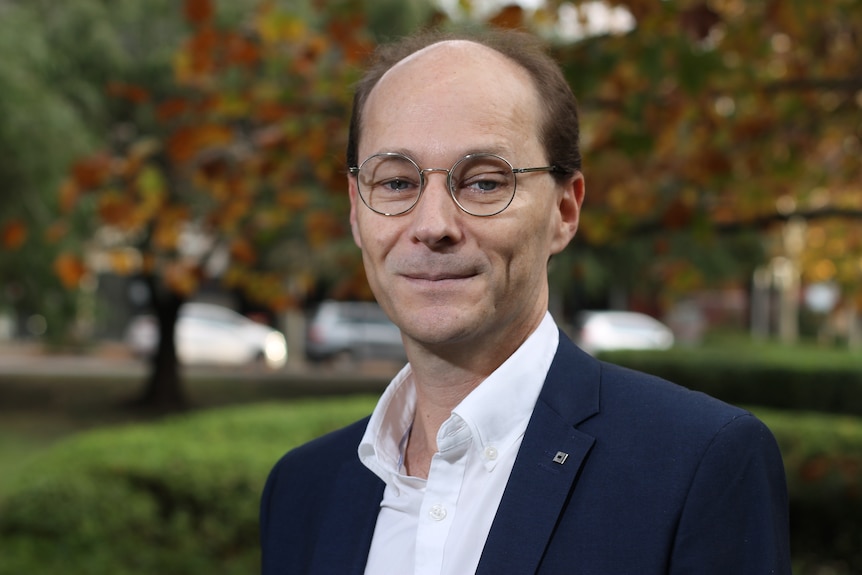 portrait shot of William Bowe with blurred autumn trees behind him