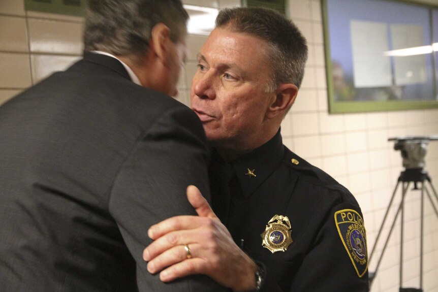 Webster police chief Gerald Pickering (R) embraces another man after addressing the media.