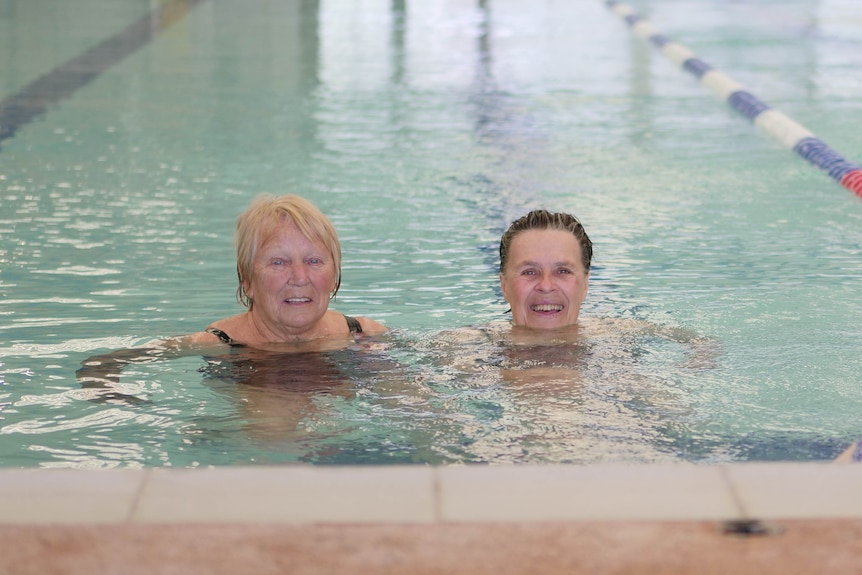 Two women floating in the water in an indoor pool