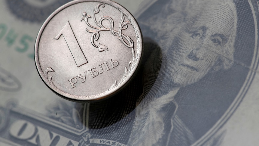 a Russian rouble coin rests on top of a US dollar banknote with george washington's face on it in this picture illustration