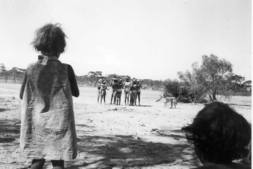 A black and white photo of children gathered together at Yalata performing a song.