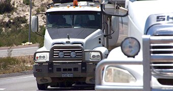 Two trucks driving on a highway.