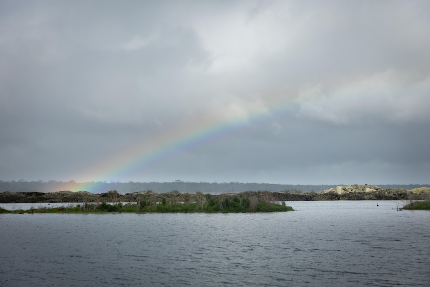 Lake with a cloudy sky and a rainbow.