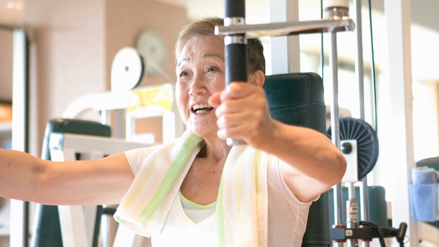An older woman using a weight machine at the gym.