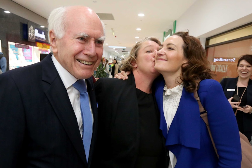 Georgina Downer gets a hug from a voter while John Howard looks on
