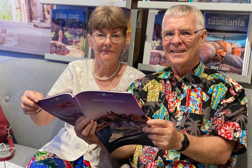 A man and woman reading a cruising brochure