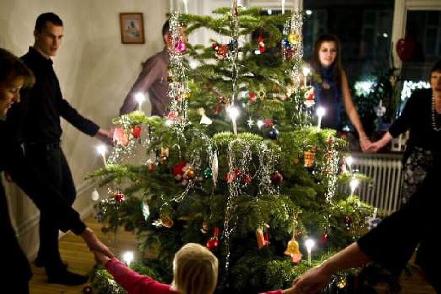 People joining hands around a brightly decorated tree