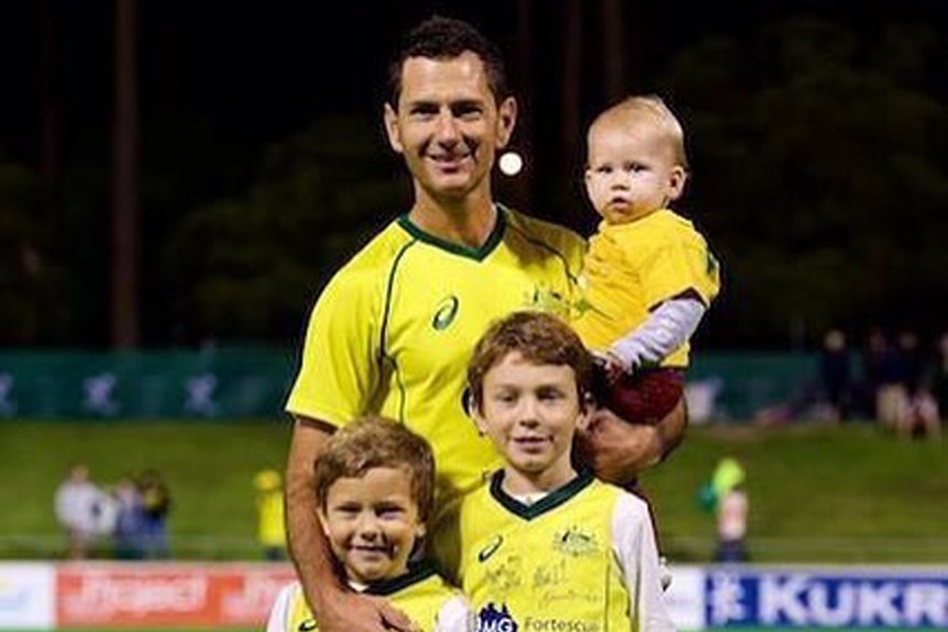 Australian hockey player Jamie Dwyer stands with his two sons, Julian and Taj, and holds his baby girl Zara