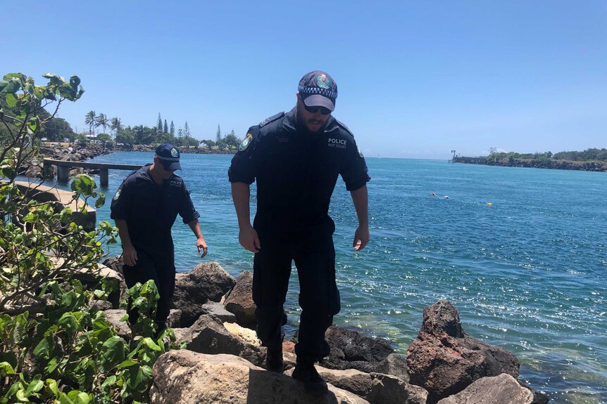 Police officers walk along the edge of Jack Evans Boat Harbour at Tweed Heads.