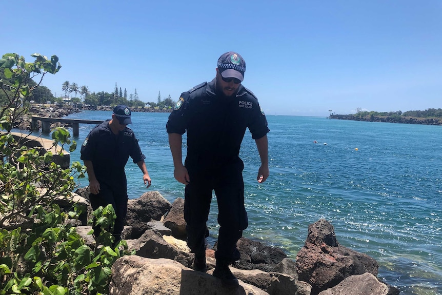 Police officers walk along the edge of Jack Evans Boat Harbour at Tweed Heads.